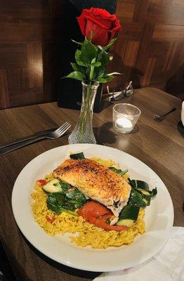 Salmon dinner over a bed of rice and vegetables