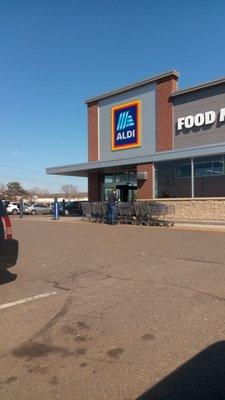 Aldi employee is wiping down and sanitizing the carts to combat covid.