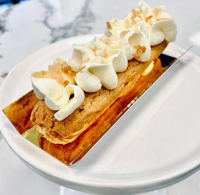 Eclair (custard filled) topped with white chocolate ribbon