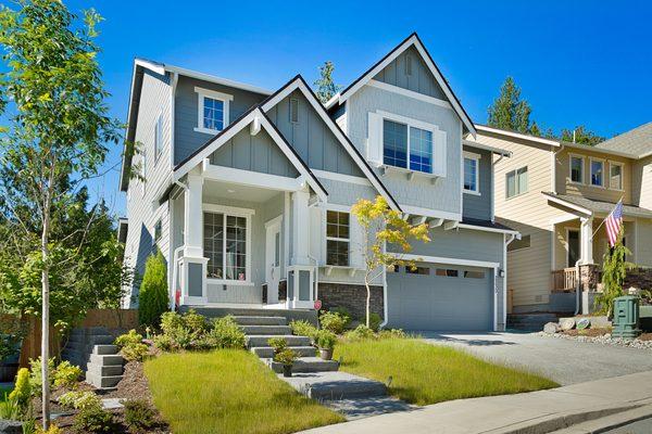 Newly constructed residence with striking curb appeal, including gabled peaks, tri-colored siding with stacked stone facade.