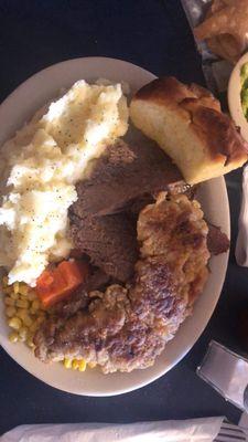 Roast beef, chicken fried steak, mashed potatoes, corn and carrots with yeast roll