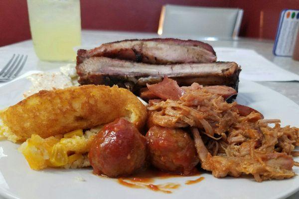 Plate with pork ribs, sausage, pulled pork and a cornbread casserole.