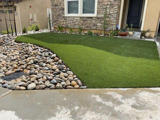 Front yard complete with artificial grass and river rock