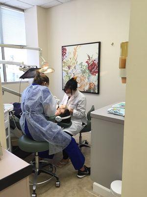 Dr. Fundora and her Assistant Darenka working on a patient while he watches live streaming on Netflix and Amazon Video.