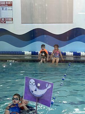 My kids left on the side of a pool, instructor busy across the pool with her back turned.