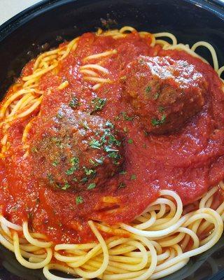 A hearty bowl of spaghetti and meatballs, garnished with fresh herbs and a rich tomato sauce from Genova's To Go.