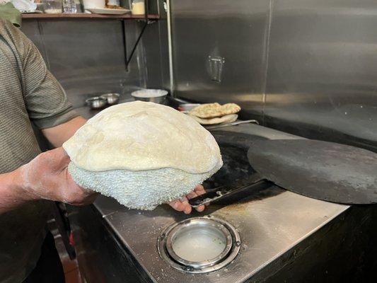 Naan placed on a pillow to stick it to the side of the hot oven.