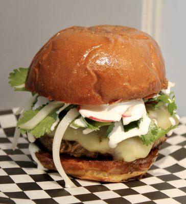 Quesobirria Stuffed Burger. Patty stuffed with birria beef, topped with pepperjack cheese, cilantro, onions, radish, salsa & Mexican crema.