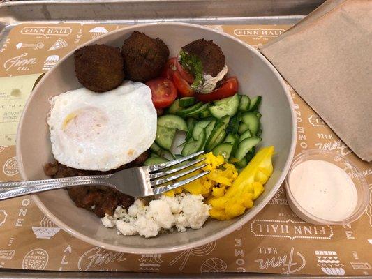 Egyptian breakfast. Fava bean stew with egg, falafel, veggies, feta with dressing on the side.