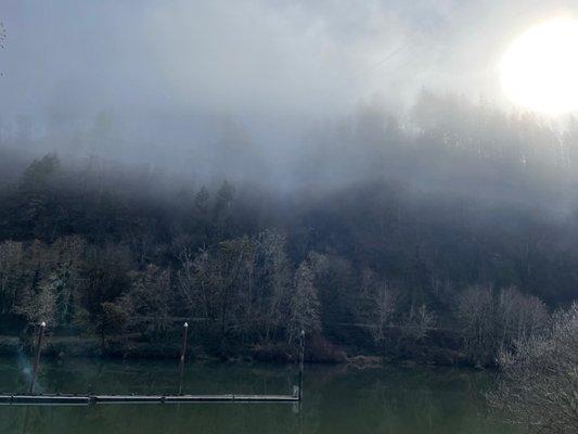 The sun rises above the ridge line and begins to dissipate the fog.