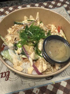 Poke bowl with salmon, cucumber, cabbage, seaweed salad, onions and siracha aioli.