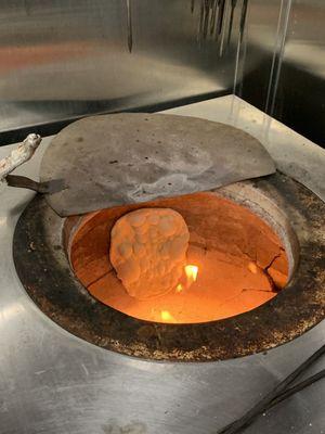 how they cook naan bread by sticking it to the side of the clay oven.