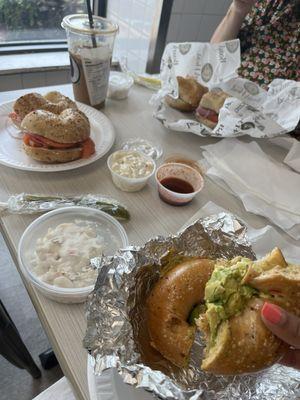 Sundried tomato bagel with egg cheese and avocado and two lox bagels with pickles and macaroni salad.