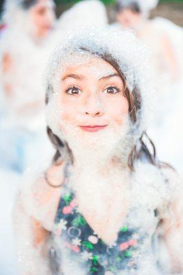 girl having fun in the foam at her foam party birthday!