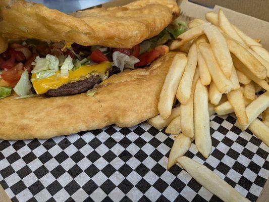 Fry Bread Cheeseburger with fries.  Lettuce, tomato and onions if you like.