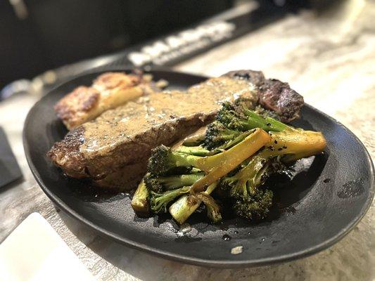 Wood-roasted Prime New York strip, with white truffle potato au gratin and black garlic sesame broccolini.