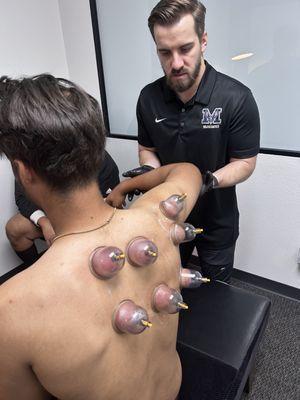 Dr. McGraw treating a baseball player with cupping and functional movement exercises