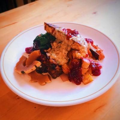 Seasonal Thanksgiving plate. Stuffing tots, brown butter tempeh, maple rosemary gravy, cranberry sauce, with a sweet delicata pickle