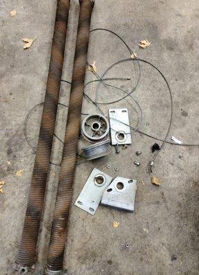 Broken garage door torsion springs cables and end bearing plates.