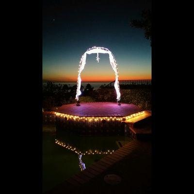 Custom lighting on the arch and pool deck for an evening wedding overlooking the ocean.