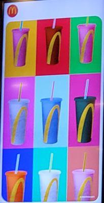 The McDonald's cups with golden arches in an artistic image on the television behind the counter.