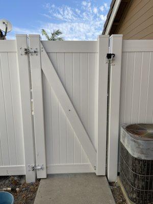 Newly installed vinyl fence with swing gate and lock mechanism (black weatherproof lock not included with install).