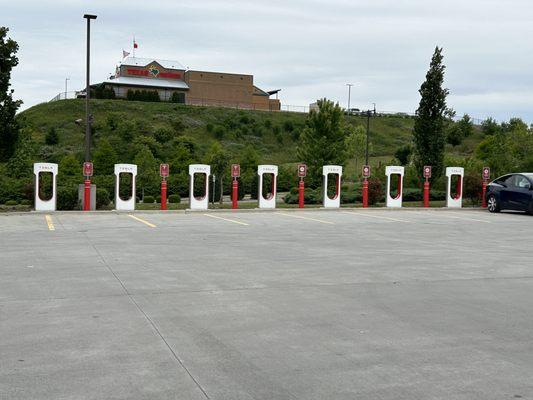 Electric vehicle recharging stations across parking lot from gas pumps.