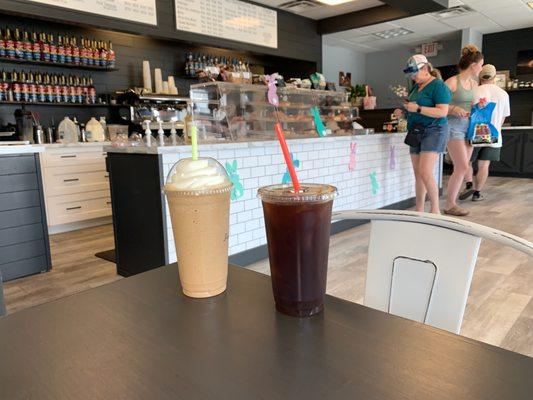 Iced frappe and Americano in front of counter