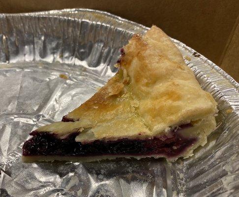 Slice of triple berry pie in its pie tin