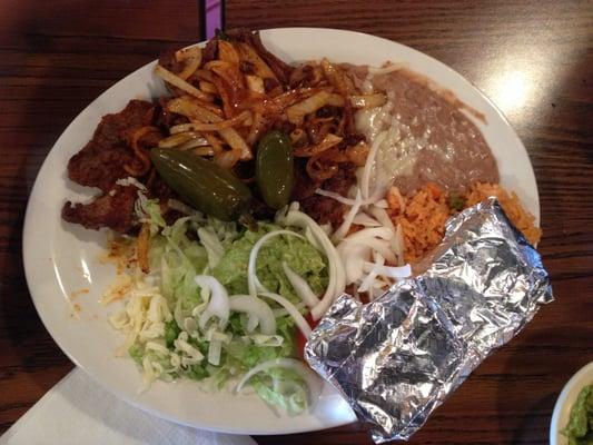 Carne Asada: Steak served with rice, beans, tomatoes, onions, and sliced avocado