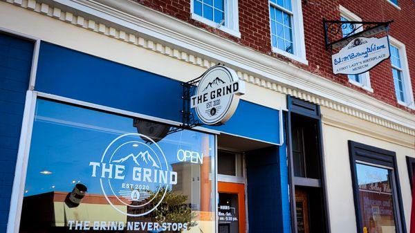 The logo on the large window has the silhouette of a mountain, stating "established 2020". The slogan is "The Grind Never Stops"