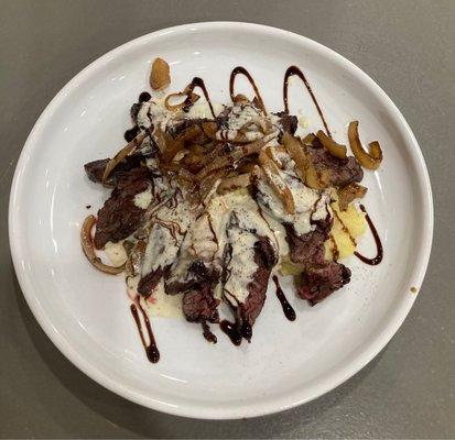 Pepper Seared Tenderloin Steak over mashed potatoes topped with a blue cheese fondue sauce and a drizzle of balsamic glaze.