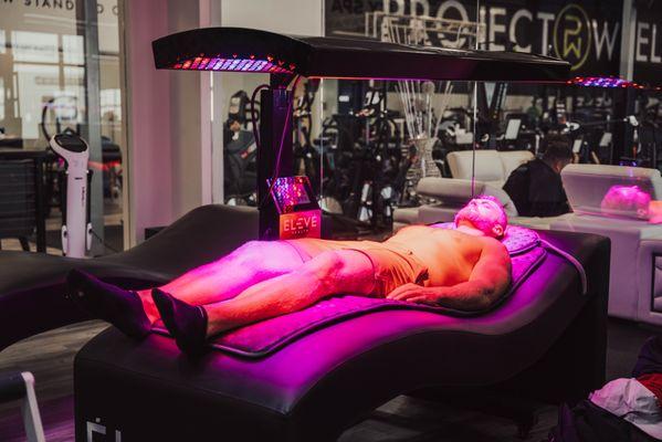 Client receiving vibro-acoustic and red light therapy, enhancing relaxation, reducing inflammation, and promoting overall wellness.