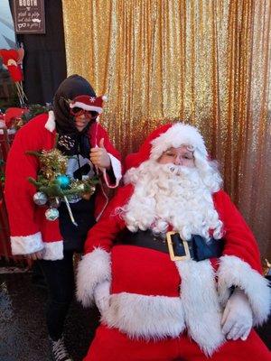 Shawn and Santa wearing her award winning Ugly Sweater creation with tree provided by Santa and Sons. Awesome Santa comes back every year.