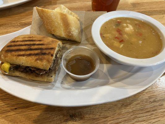 Steakhouse panini and au jus, with white bean chili and bread as a side.