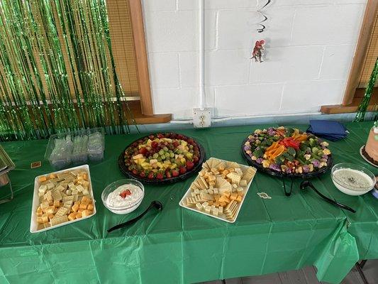 Two cheese boards, a veggie tray and a fruit tray, with accompanying dips