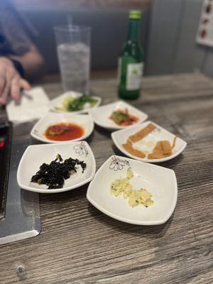 Banchan- Korean potato salad, seaweed salad, tofu strips, cucumber kimchi, kimchi, salad.