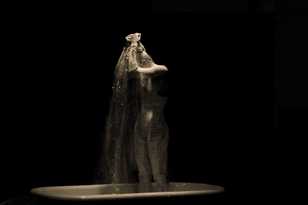 Hannah Simmons bathing in flour getting ready to dance alongside tar paper. Part of "Sarah Fetterman: Past Selves".