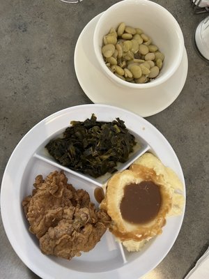 Fried chicken thigh, mashed potatoes and gravy, collards, and baby Lima beans