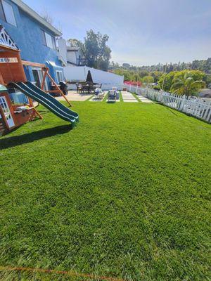 A scope of the backyard project. Real grass, turf between the concrete squares & retaining wall that continues down the side of the house.