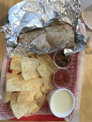 Veggie burrito, chips and cheese dip.