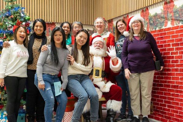 Volunteers taking a group photo with Mr & Mrs Clause at the 2022 Cookies & Cocoa with Santa event hosted by Harvey Green PTA in Fremont, CA