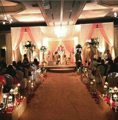 Aisle, double mandap, floral ganesh backdrop, soft amber lighting
 Wedding