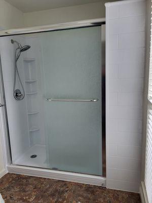 Hall bath after with walk-in shower, partial wall and bench inside.