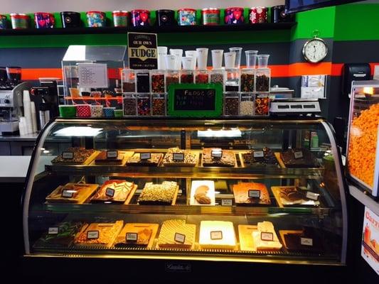 Homemade fudge in the glass display, popcorn to the right and popcorn tins above.