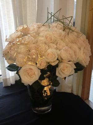 White roses with gold leaf draped over the petals and thin, green vines sculptured in random geometric patterns for modern twist