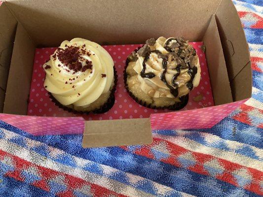 Two gluten free vanilla cupcakes, one  with red velvet cream cheese icing and and  the  other peanut butter cup frosting