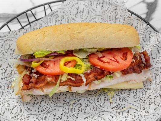 This is a photo of the turkey bacon with tomatoe, lettuce, red onion, banana pepper, and italian dressing.