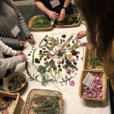 A group of adults assembling a plant mandala, led by a horticultural therapy intern.