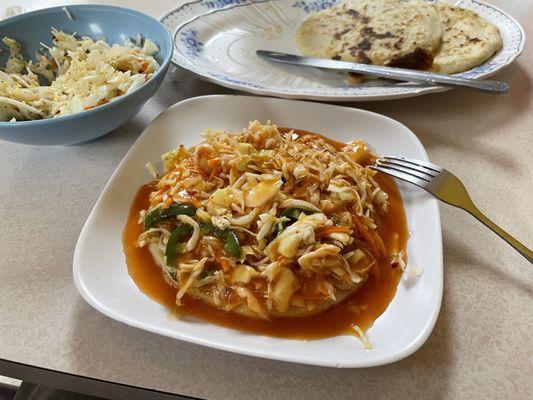 Chicken pupusa smothered in curtido and tomato sauce.